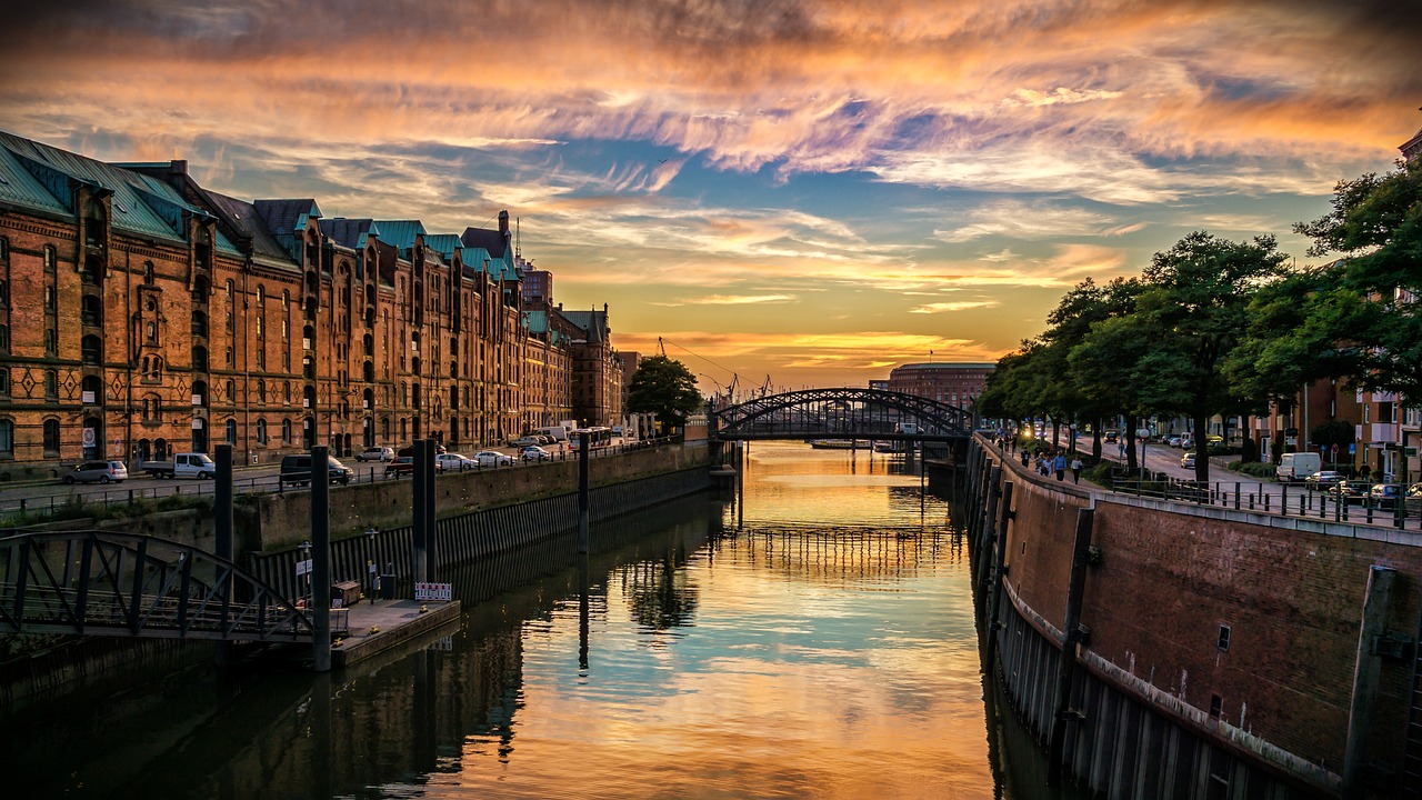Die Speicherstadt in Hamburg bei Sonnenuntergang mit einem Kanal, Bruecken und historischen Gebaeuden.