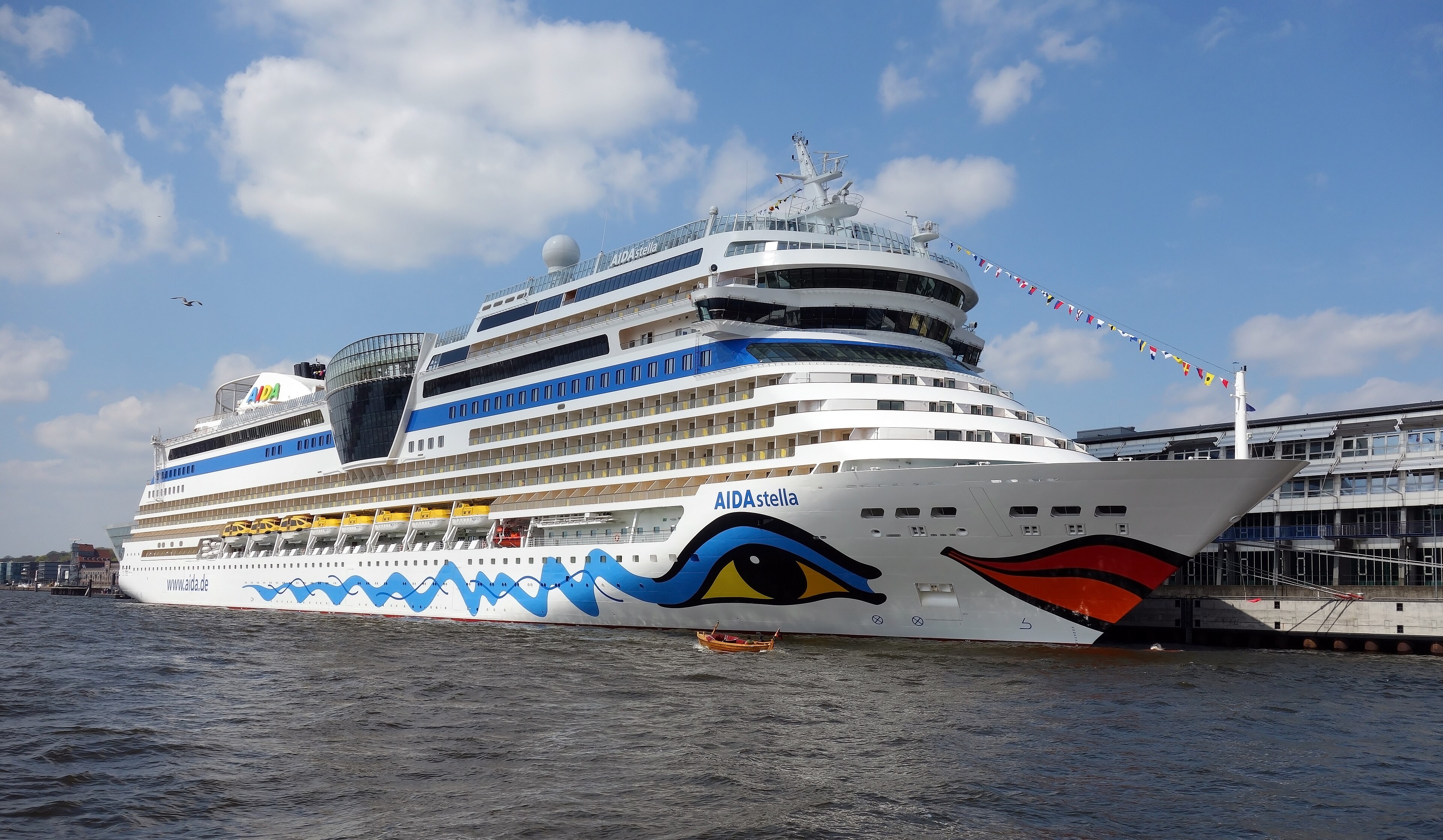 Ein großes Kreuzfahrtschiff der AIDA-Flotte liegt im Hafen am Kai.