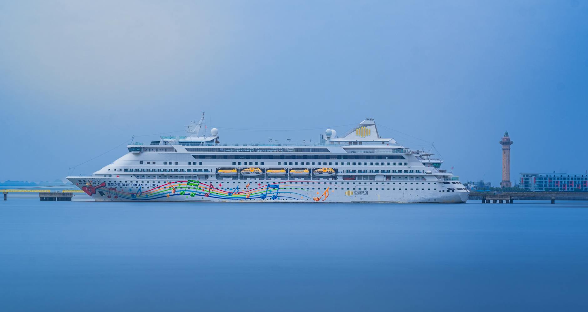 Ein großes weißes Kreuzfahrtschiff mit bunten Noten und dem Schriftzug 