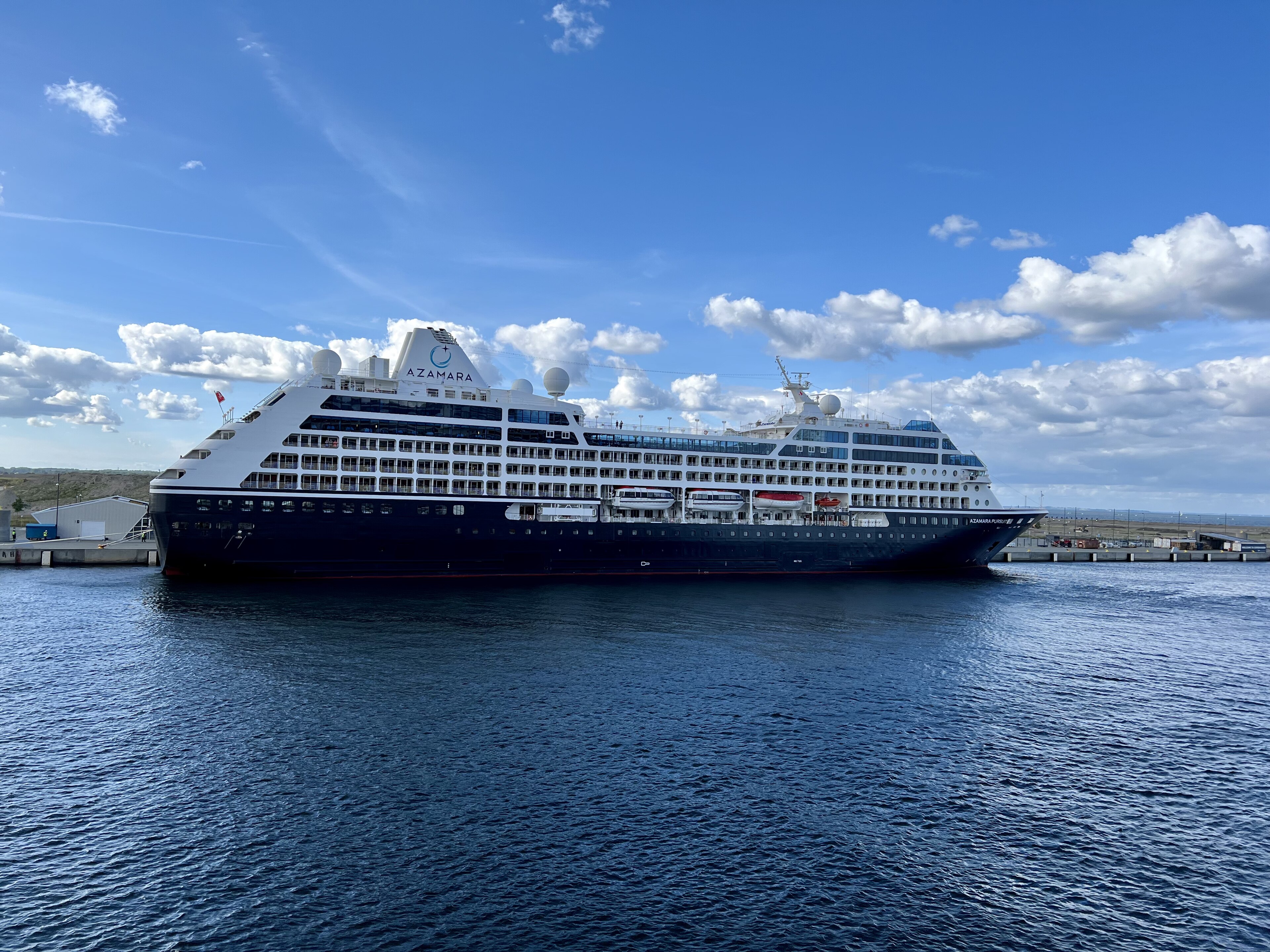 Ein großes Kreuzfahrtschiff der Marke Azamara liegt im Hafen vor Anker.