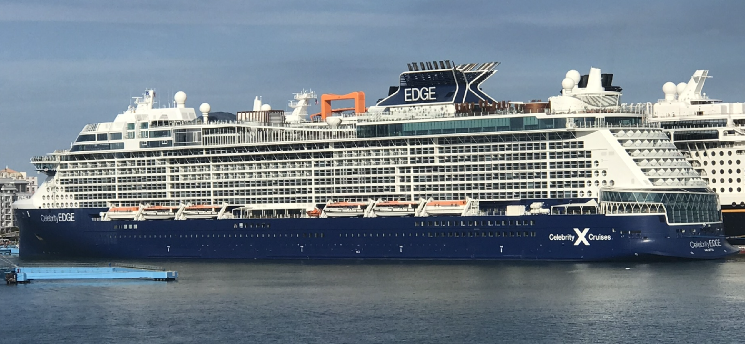 Ein großes blaues Kreuzfahrtschiff mit dem Namen Celebrity Edge liegt im Hafen.