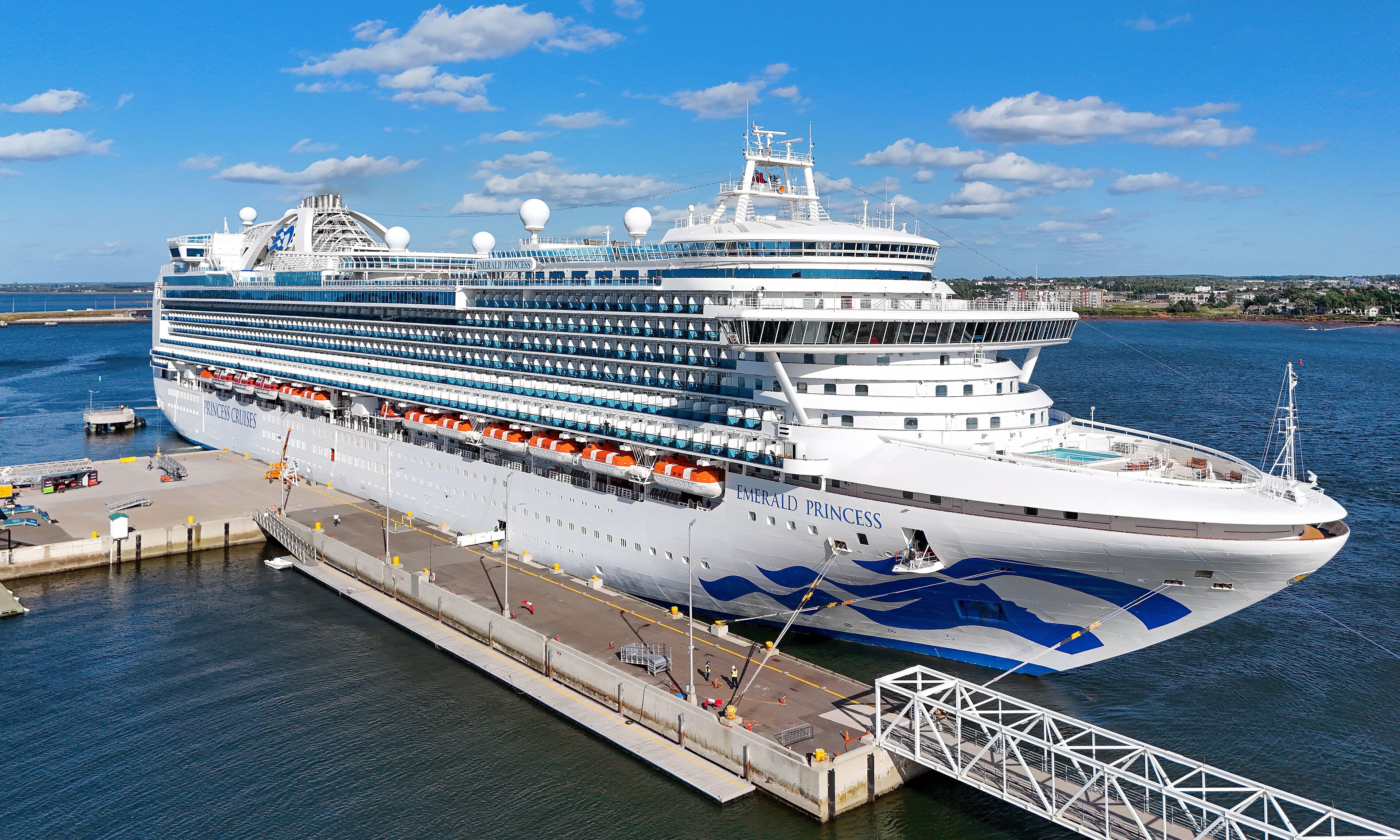 Ein großes weißes Kreuzfahrtschiff namens Emerald Princess liegt an einem Pier im Hafen.