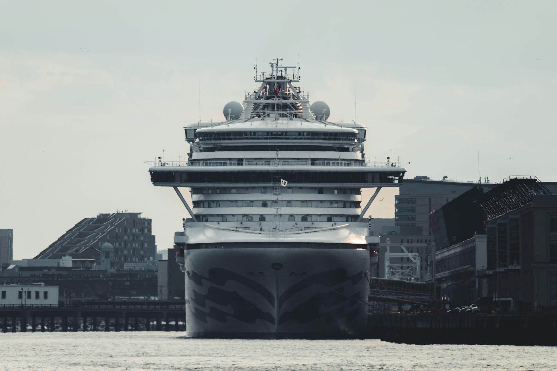 HX Expeditions Kreuzfahrtschiff - A massive cruise ship docked at an urban harbor, amidst tall buildings and clear