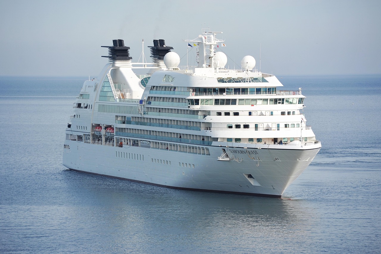 Ein großes weißes Kreuzfahrtschiff mit mehreren Decks fährt auf dem ruhigen Meer.
