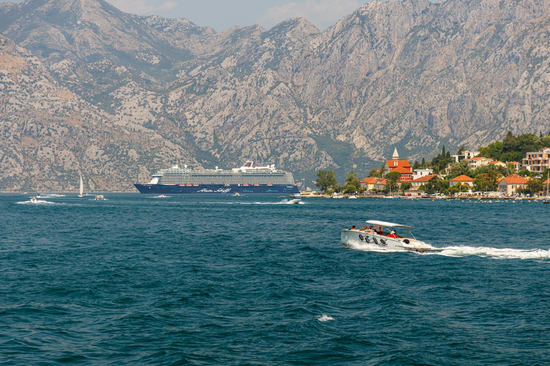 Kreuzfahrtschiff - Cruise ship and speedboat in scenic Montenegro bay with mountain backdrop, offer
