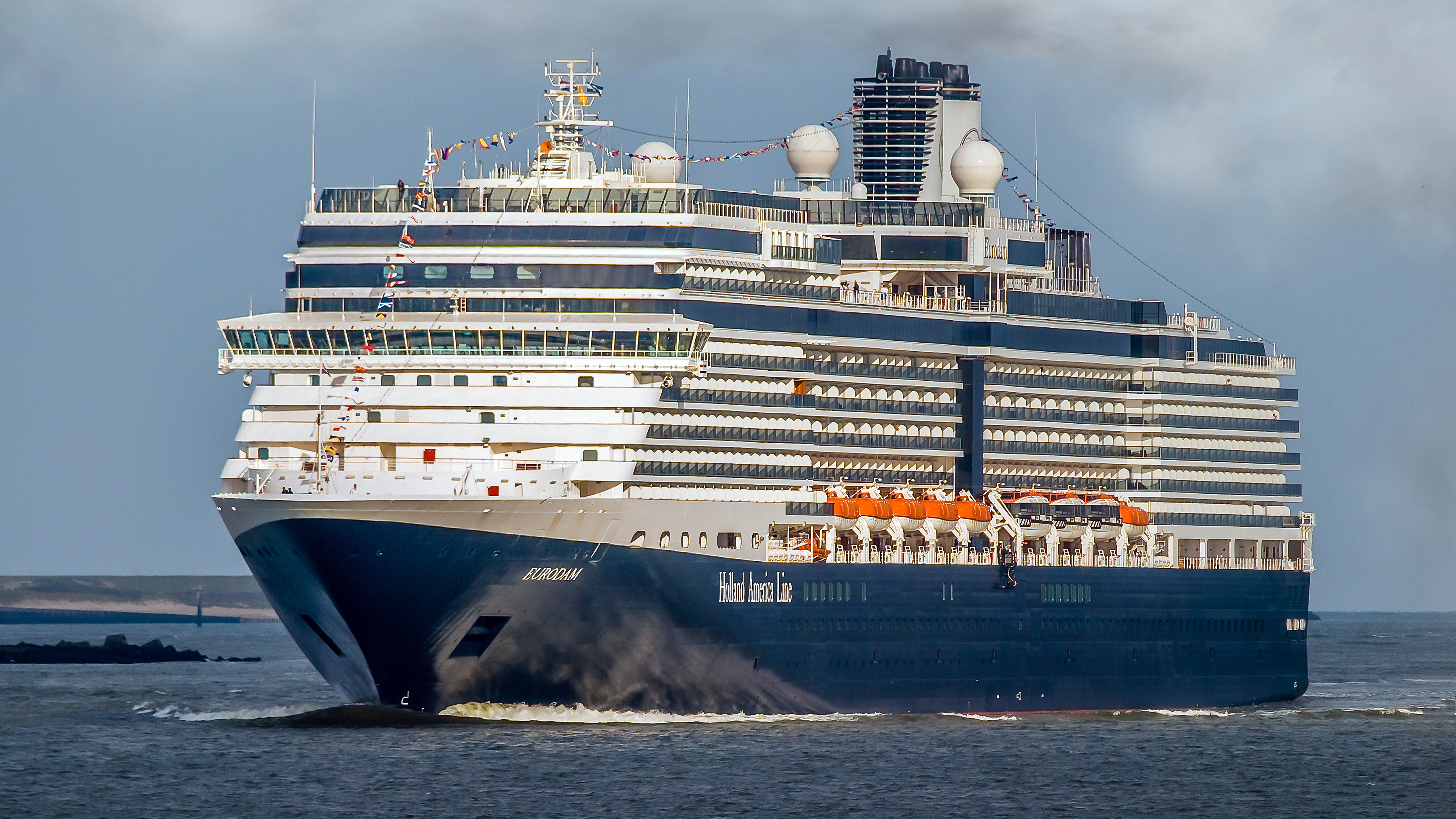 Ein großes blau-weißes Kreuzfahrtschiff namens Eurodam der Holland America Line fährt auf dem Meer.