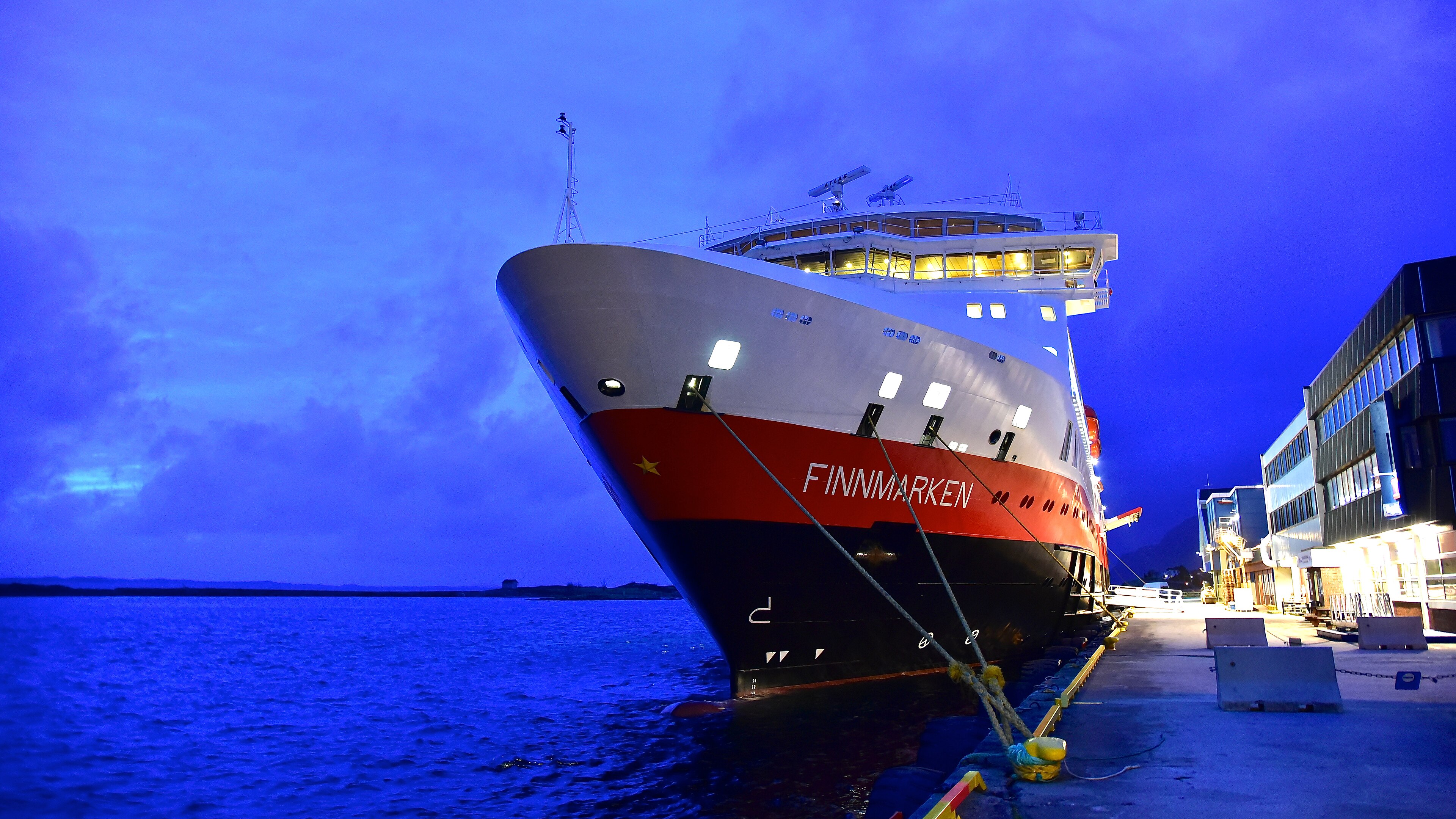 Ein großes Passagierschiff mit dem Namen FINNMARKEN liegt nachts an einem Pier im Hafen.