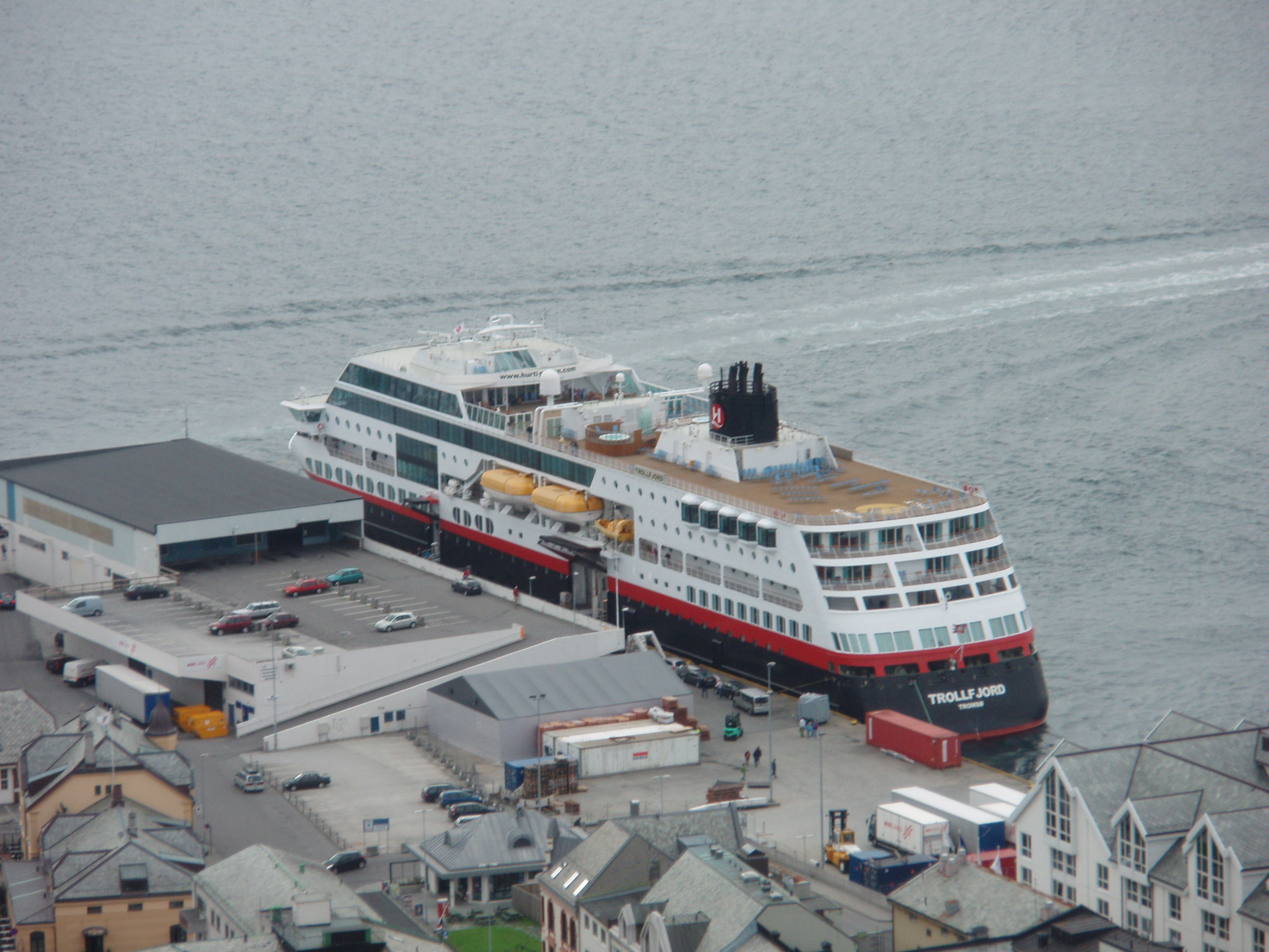 Ein großes Passagierschiff mit dem Namen TROLLFJORD liegt im Hafen neben Gebäuden und Autos.