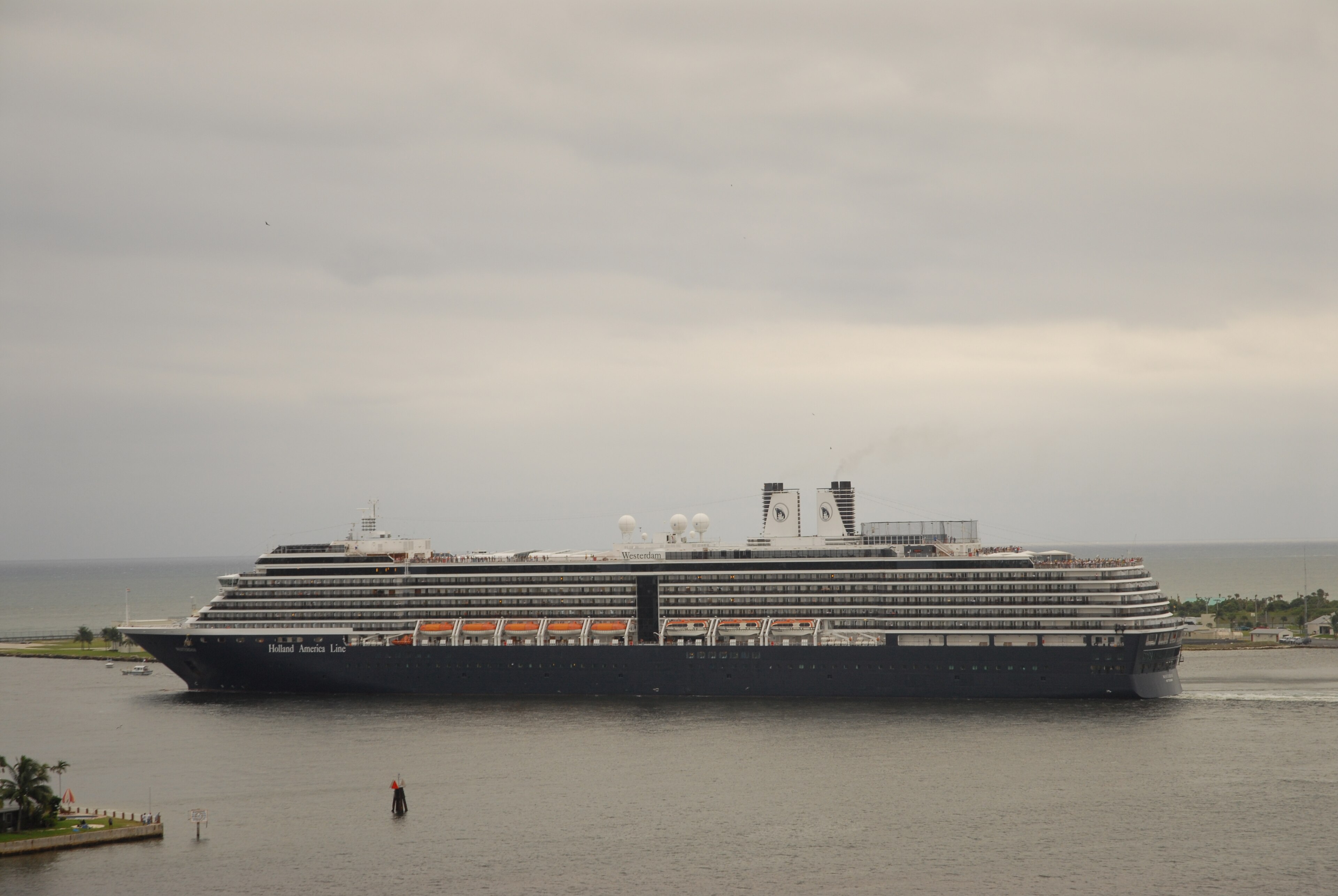 Ein großes Kreuzfahrtschiff der Holland America Line mit dem Namen Westerdam fährt auf dem Meer in der Nähe eines Hafens.