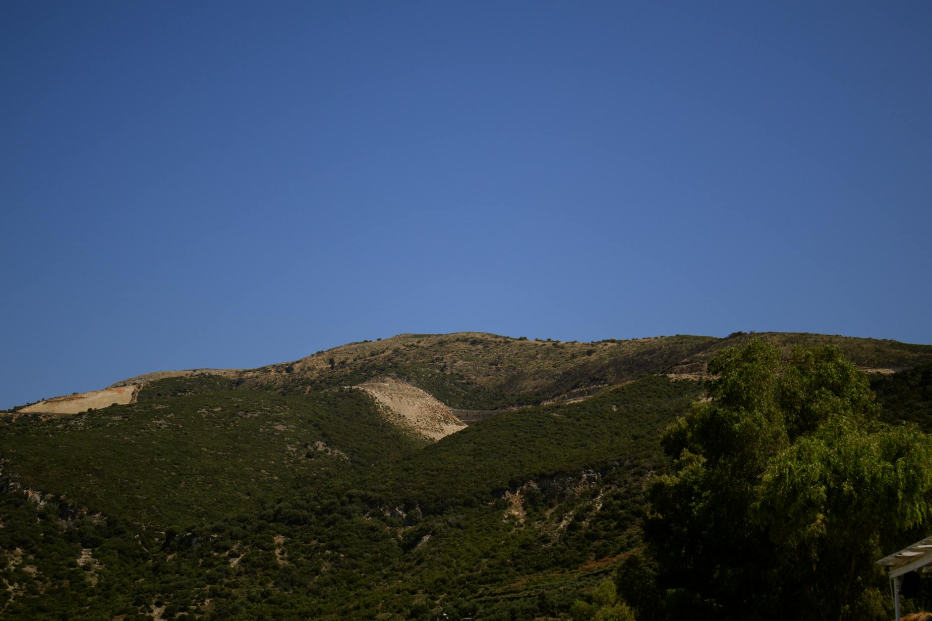 Eine bergige Landschaft mit grüner Vegetation und einem blauen Himmel.