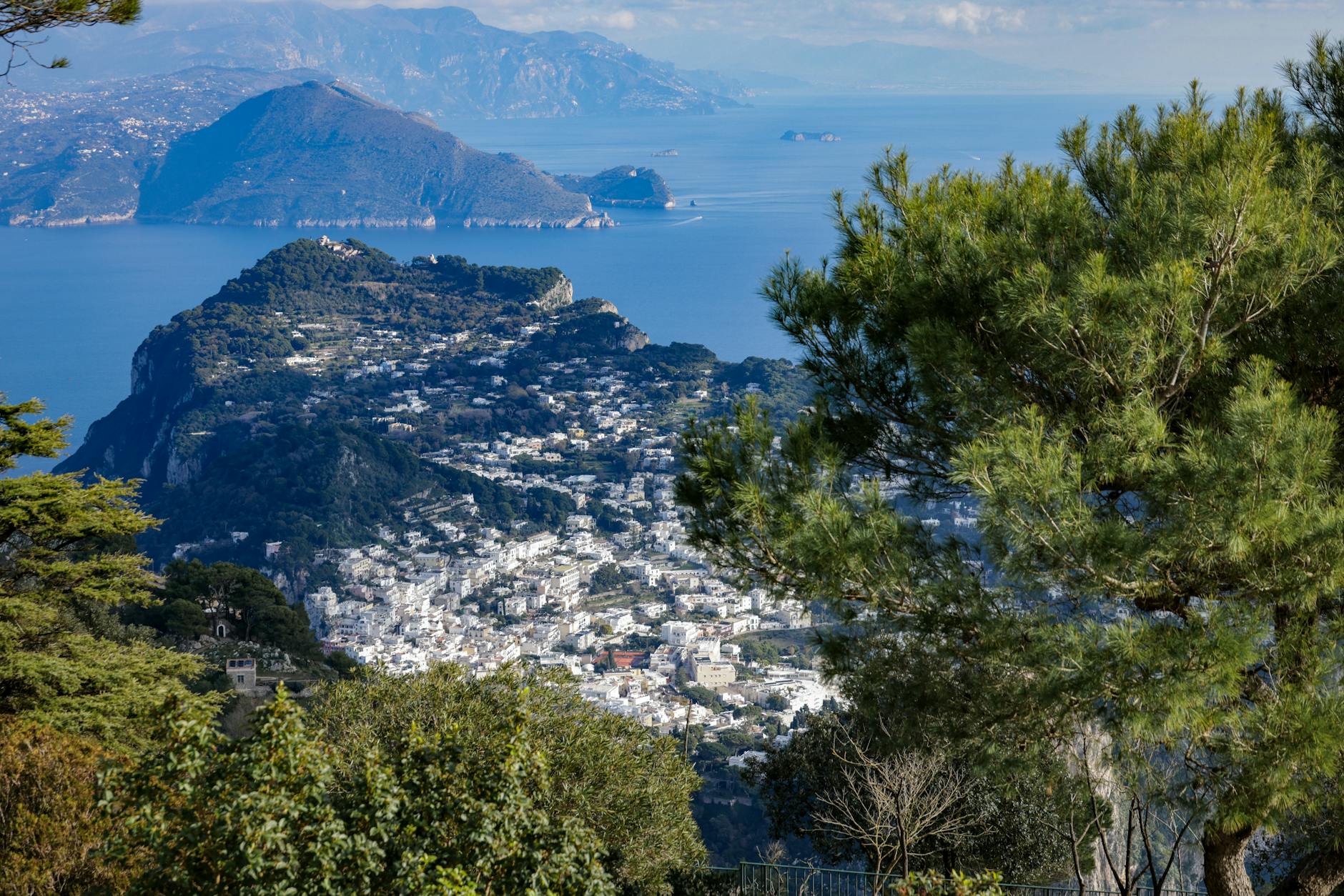 Blick auf eine weisse Stadt auf einem huegeligen Berg mit dem Meer und anderen Inseln im Hintergrund.