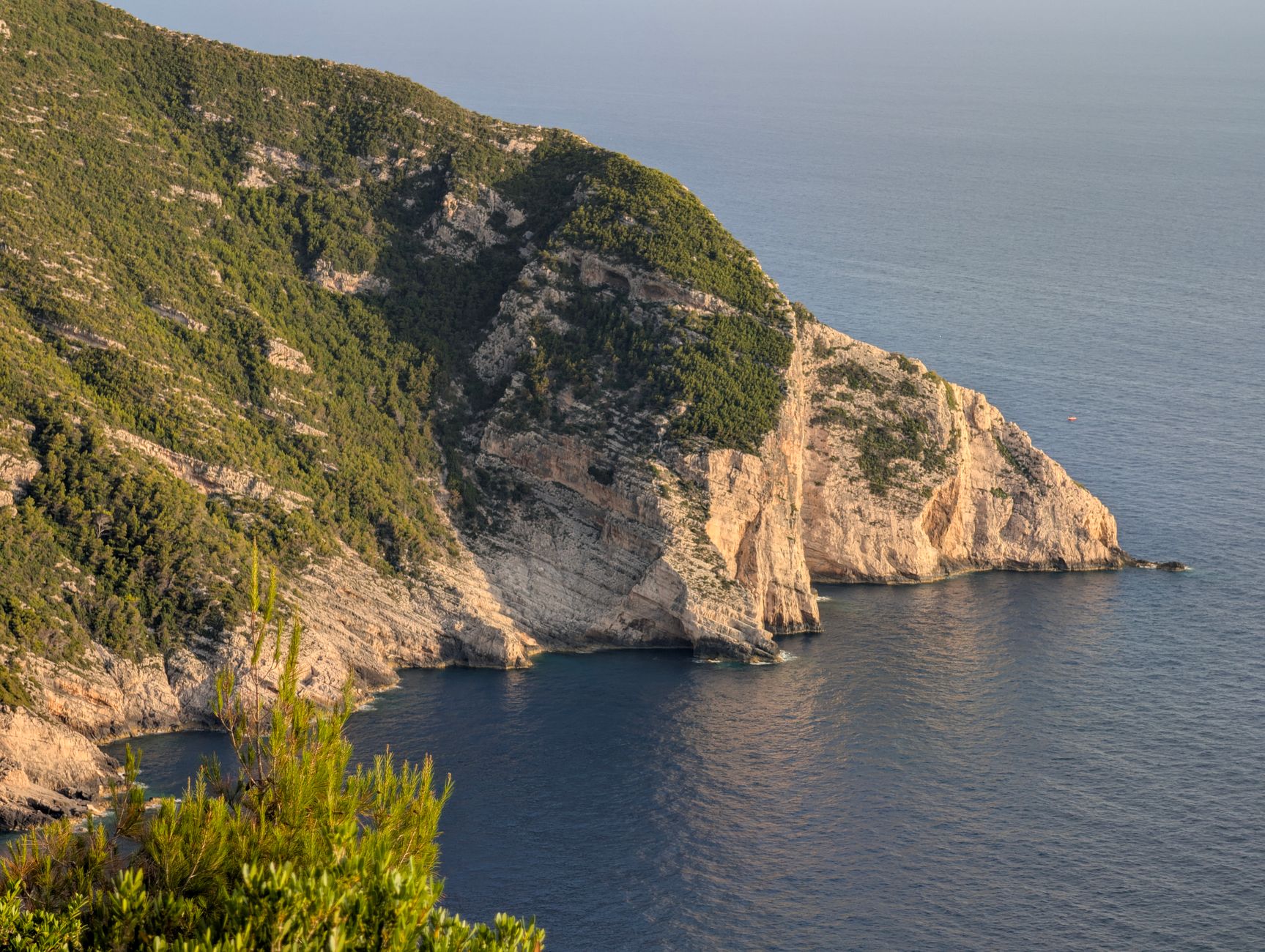 Griechenland - Dramatic cliffs covered in green vegetation overlooking the calm ocean under a w