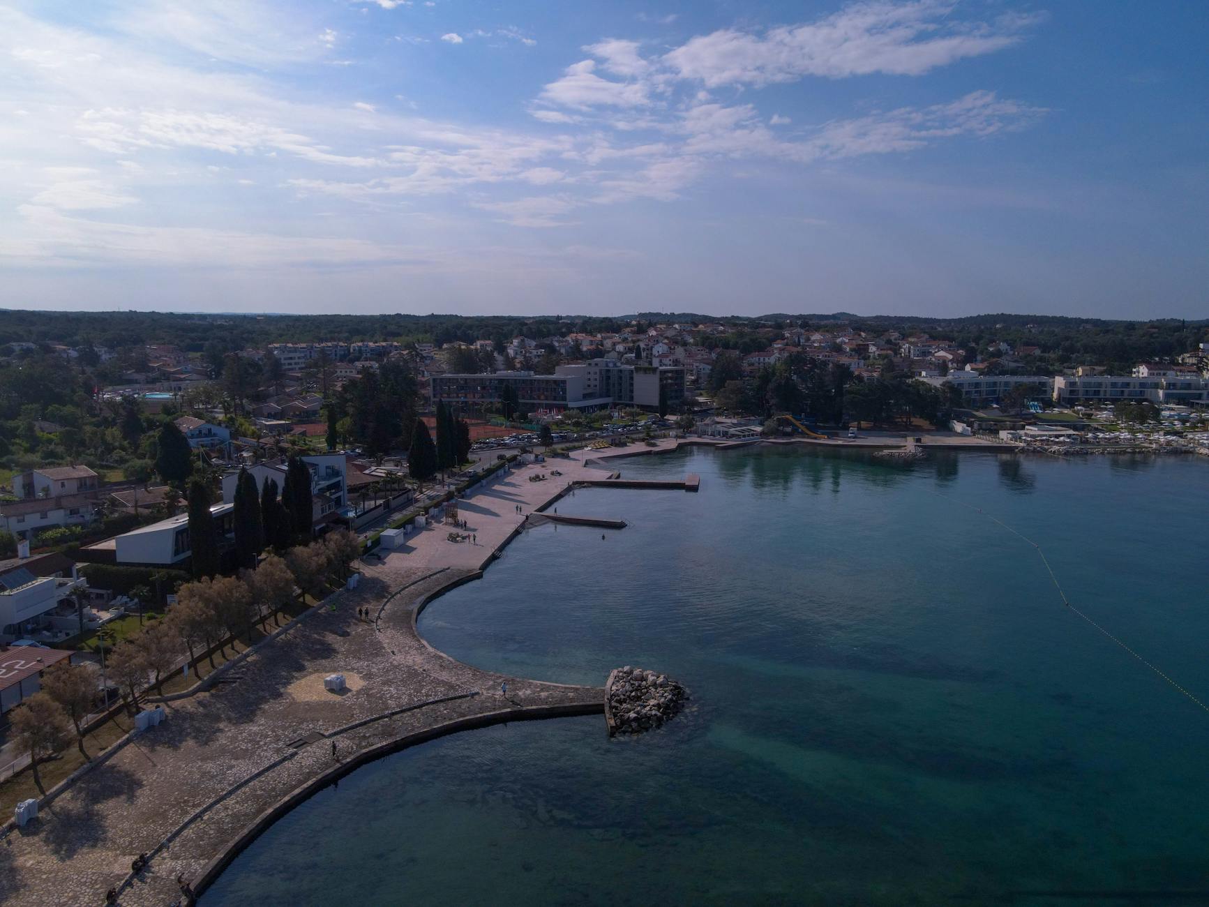 Istrien, Kroatien - Luftaufnahme einer Kuestenstadt mit einem Hafen, einer Promenade und Gebaeuden am Meer.