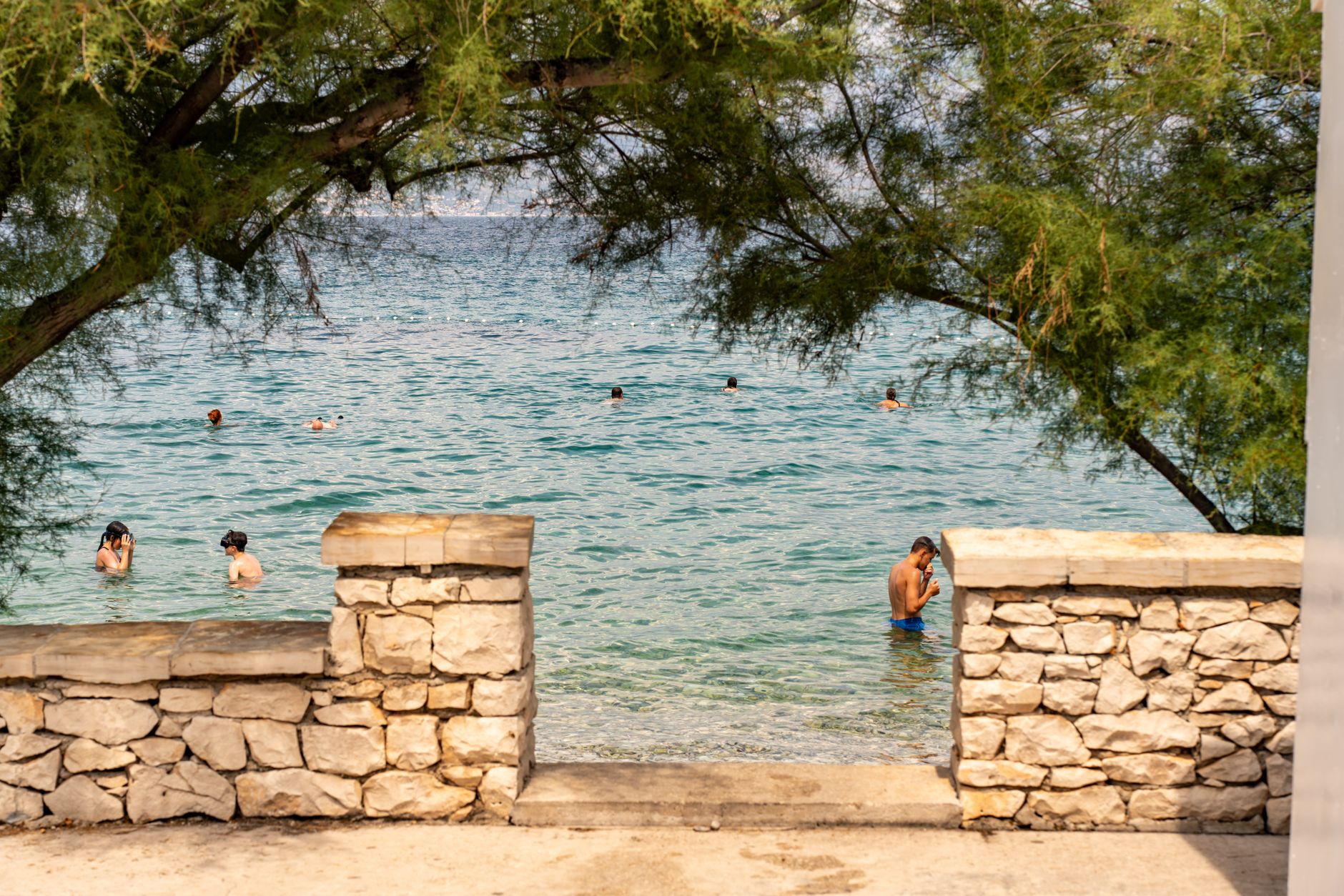 Istrien, Kroatien - People enjoying a sunny summer day swimming in the scenic waters of Supetar, Cro