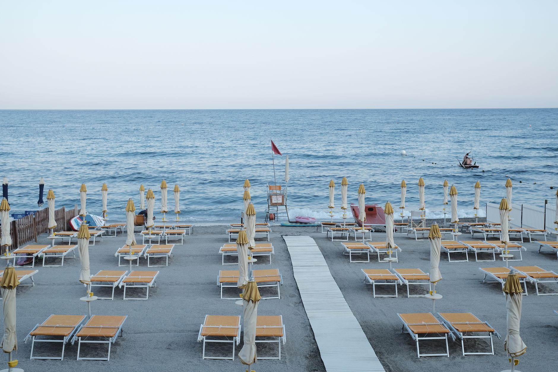 Italien - Peaceful Italian beach with empty sun loungers and umbrellas before the crowd ar