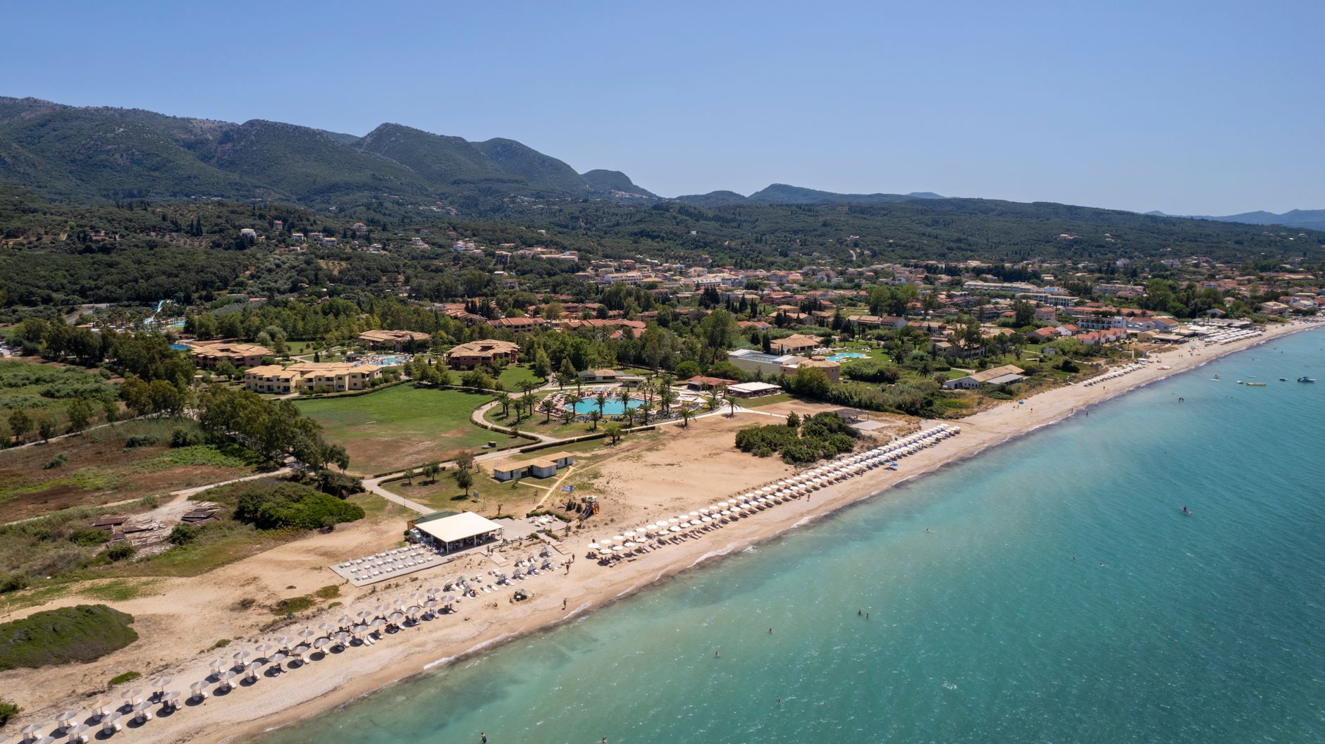 Korfu - Aerial shot of a coastline resort in Corfu, Greece with a beautiful beach and lu