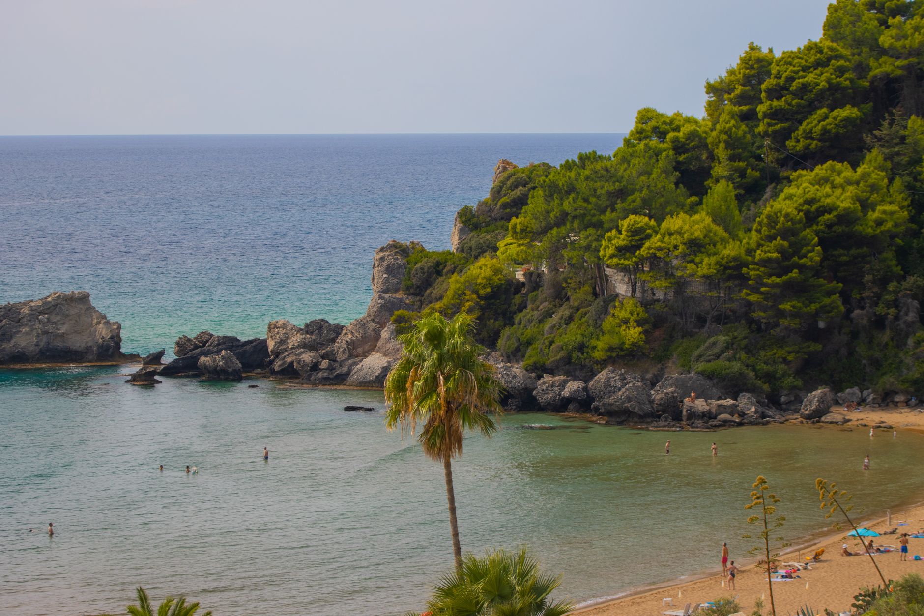 Korfu, Griechenland - A serene beach scene in Corfu, Greece, showcasing clear waters, rocky cliffs, an