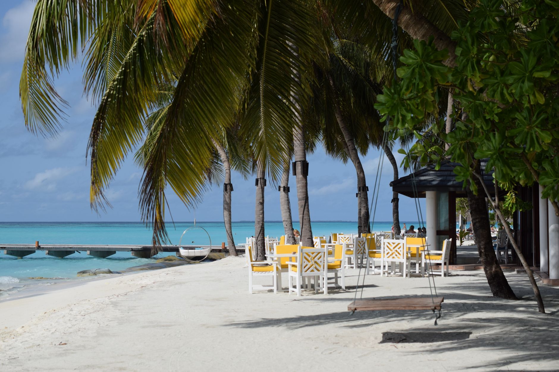 Malediven - Serene tropical beach scene with palm trees, white sand, and outdoor seating und
