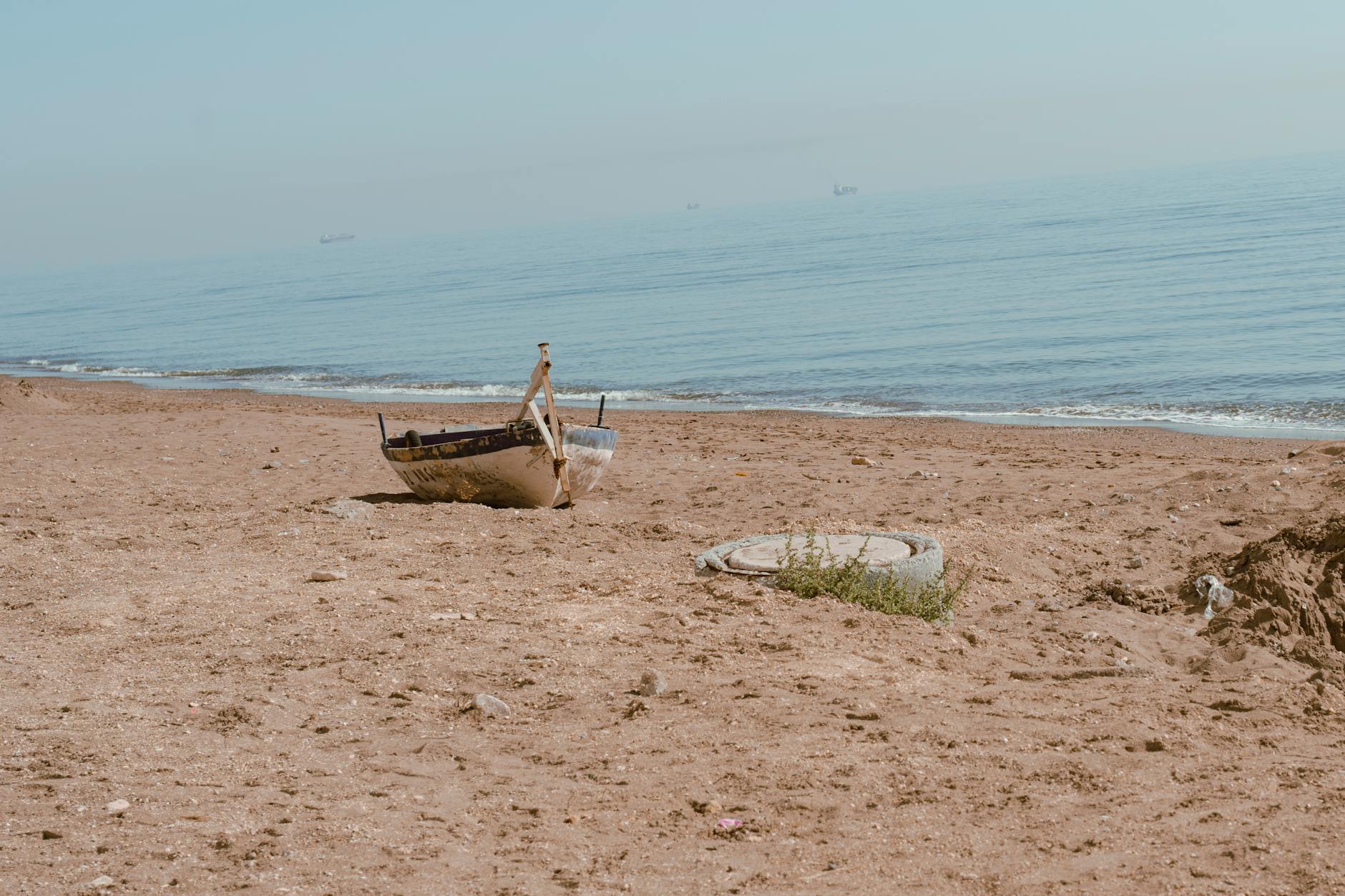 Ein kleines, verwittertes Boot liegt am sandigen Strand, das Meer ist im Hintergrund zu sehen.
