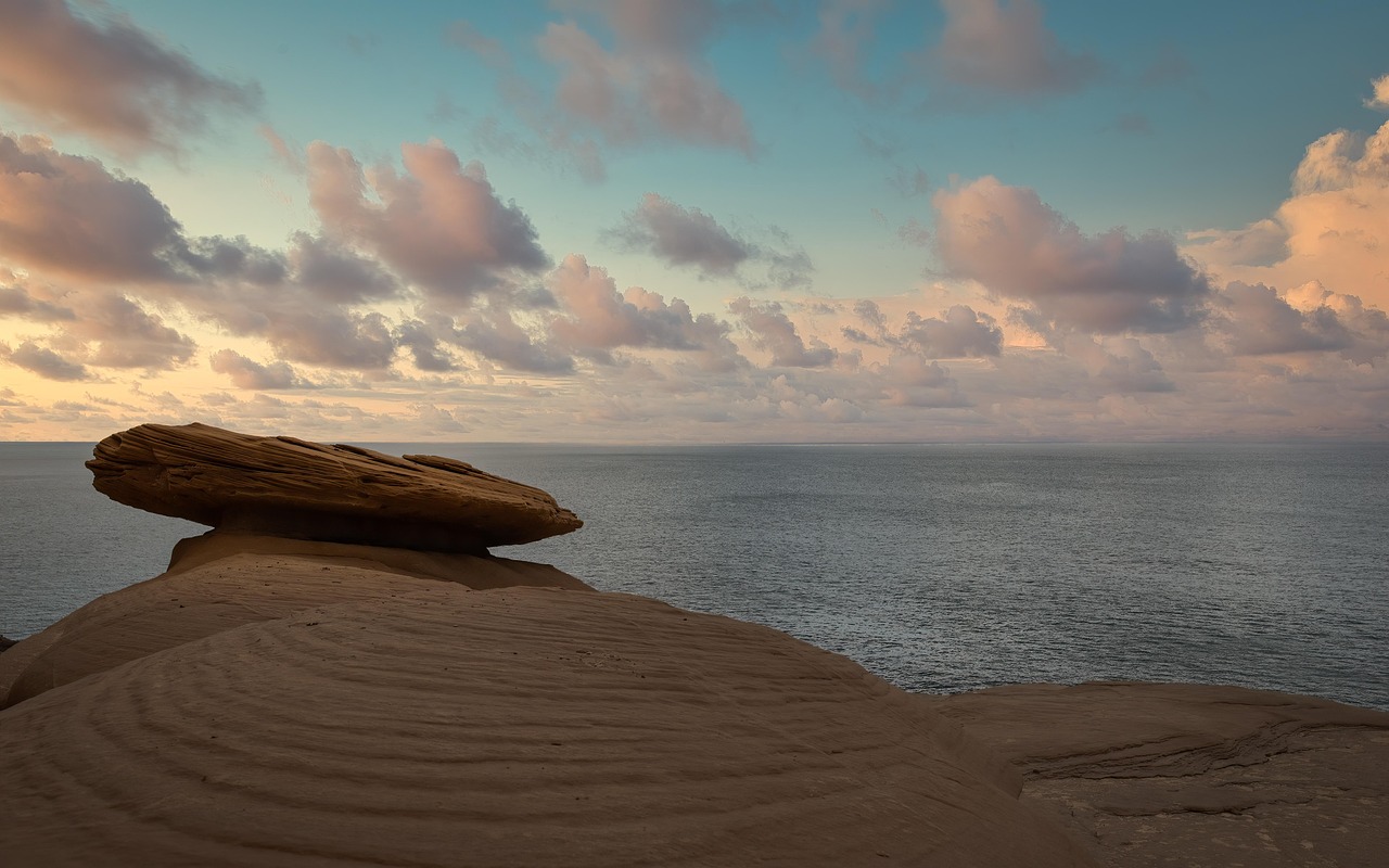 Eine markante Felsformation auf einer Klippe mit Blick auf das Meer bei Sonnenuntergang.