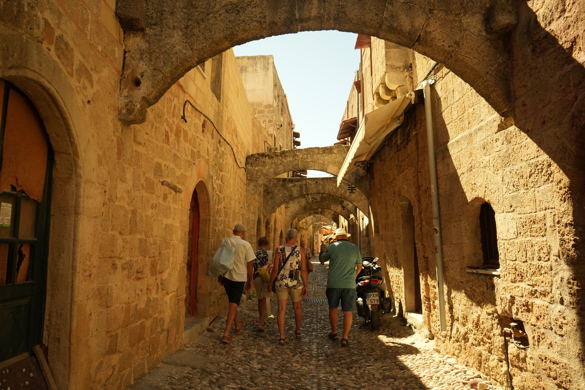 Rhodos, Griechenland - Tourists walking through cobblestone streets under historic arches in Old Town R