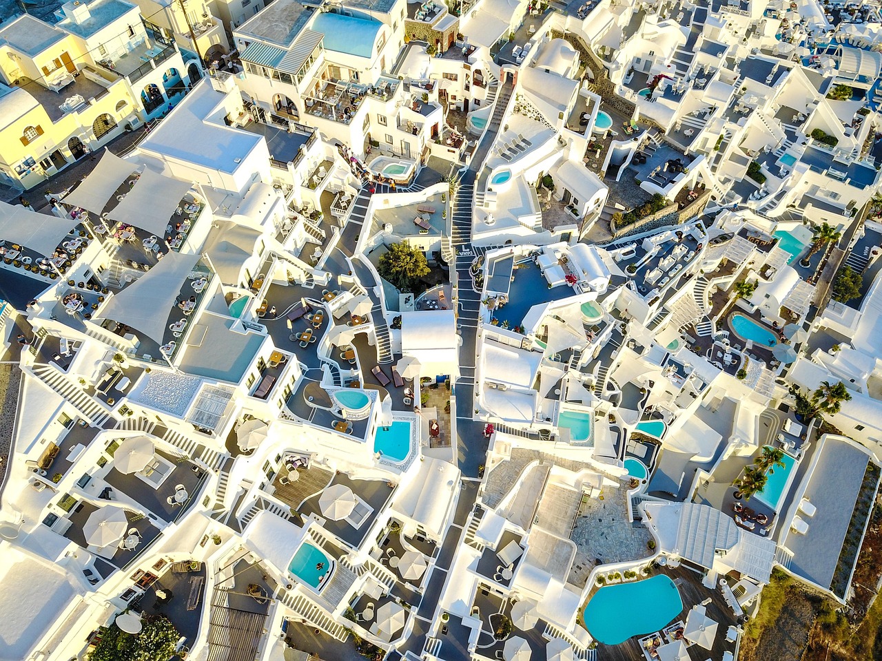 Luftaufnahme einer Hotelanlage mit vielen weißen Gebäuden, Pools und Terrassen.