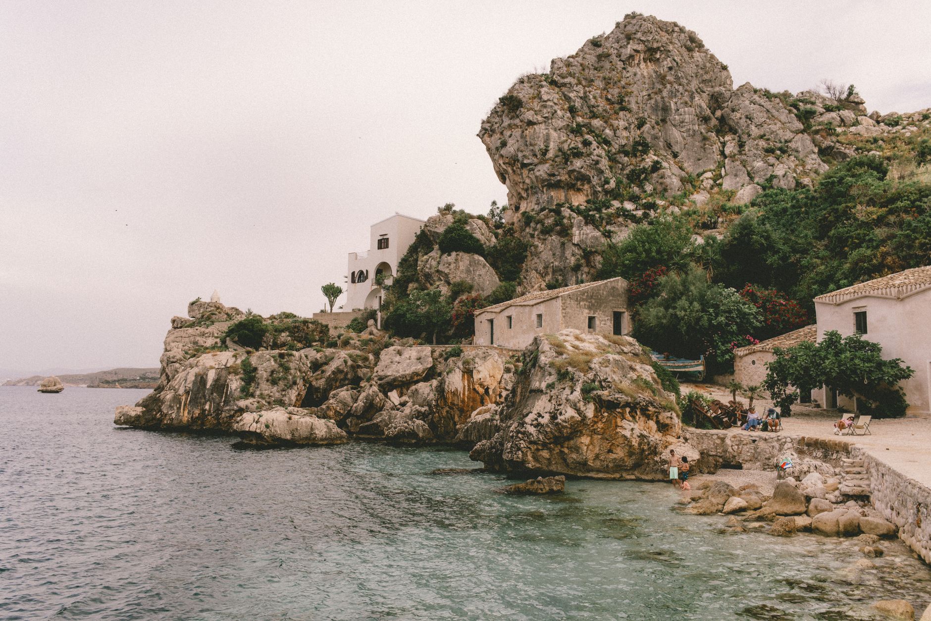 Sizilien, Italien - Scenic seaside village nestled among rocky cliffs with serene waters.