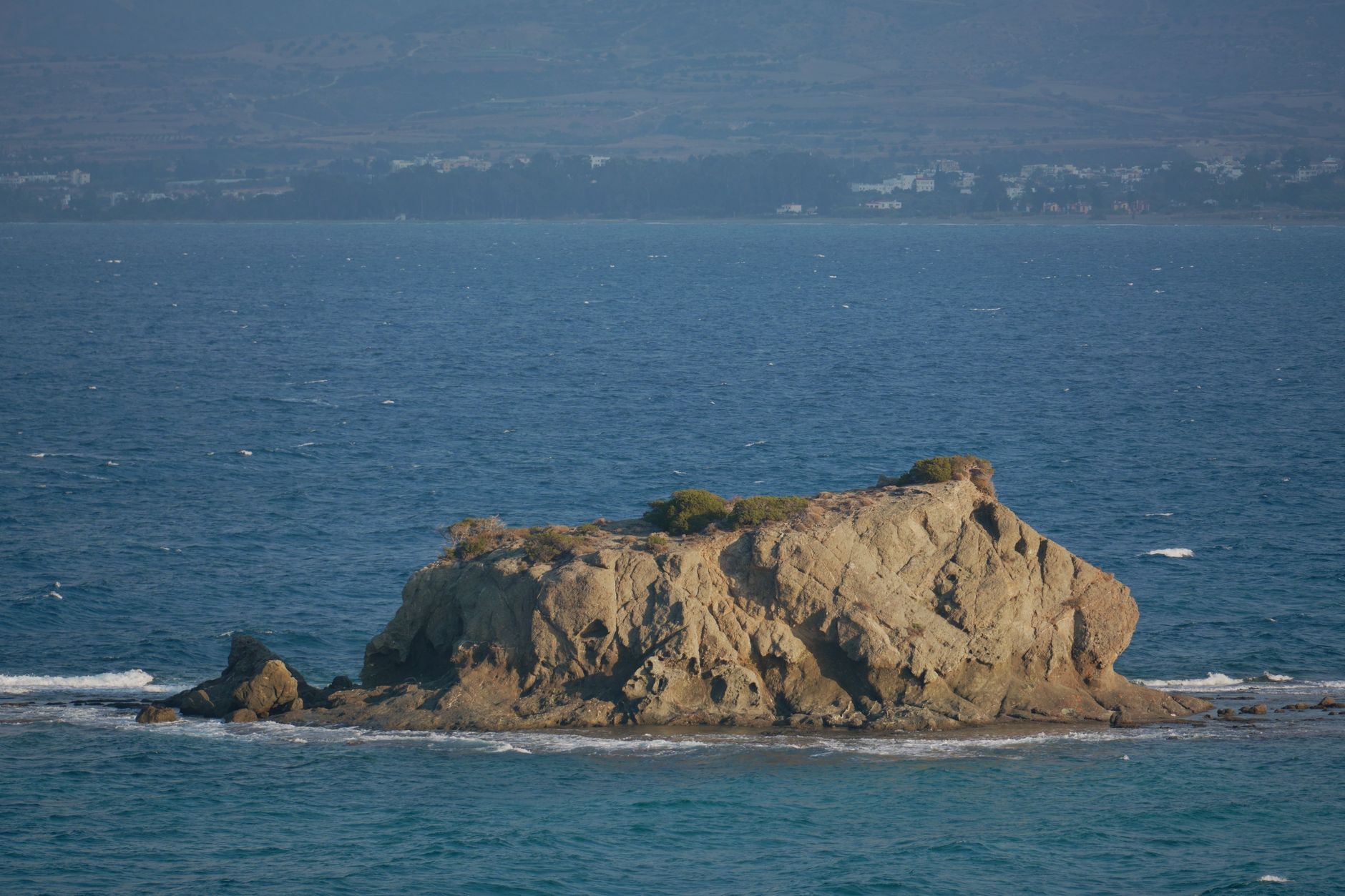 Zypern - Serene view of a rocky island in the calm Mediterranean Sea during daytime.