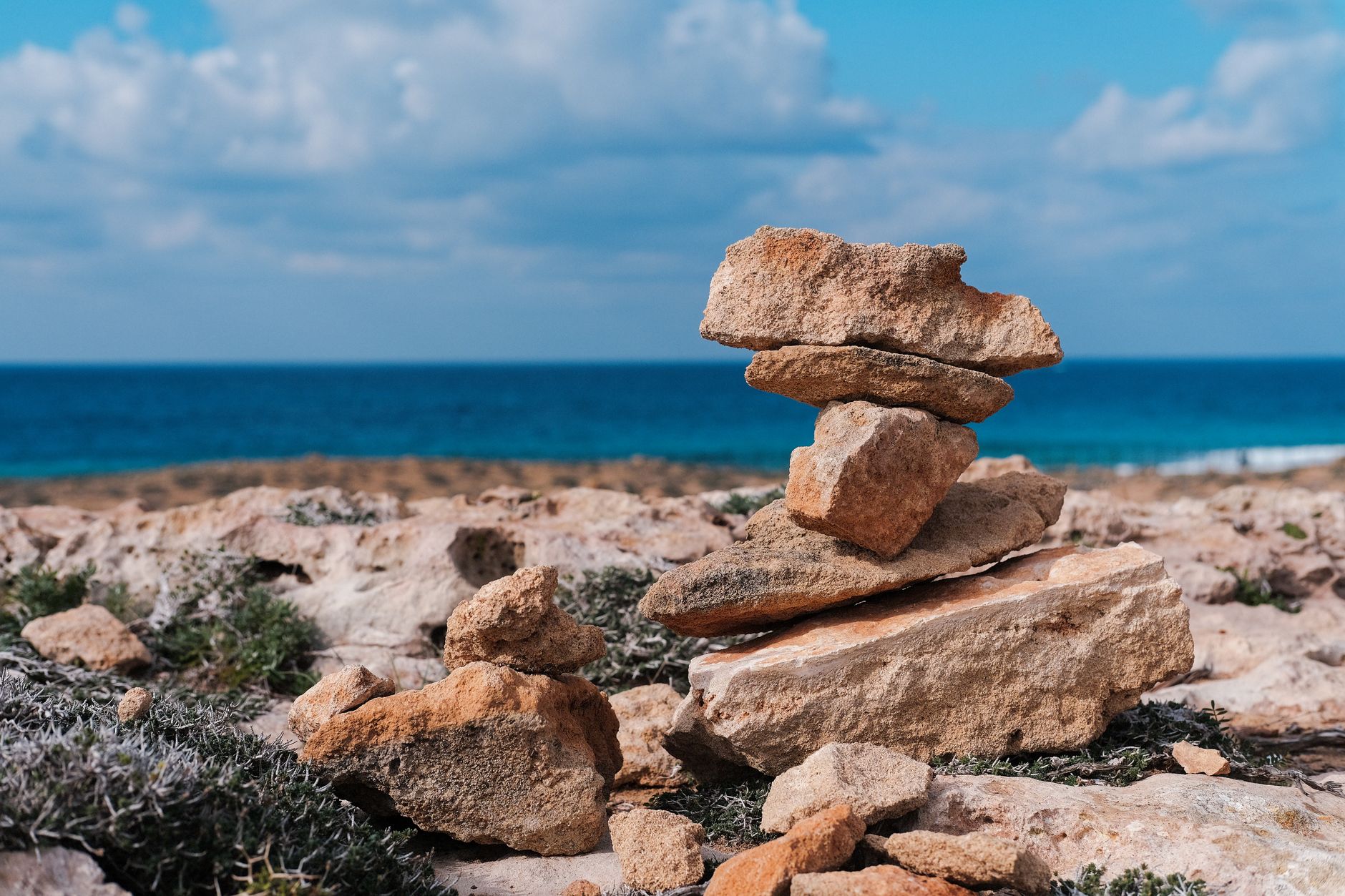 Zypern - Serene view of balanced stones on rocky coast with blue sea and sky in Cyprus.